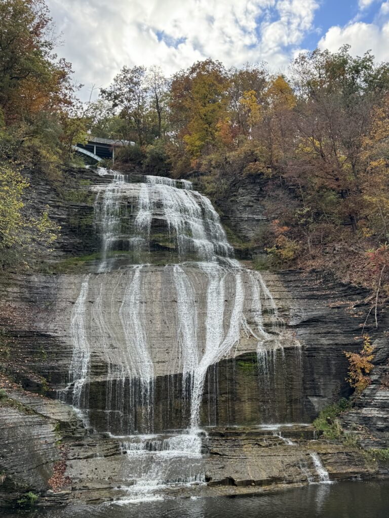 Shequaga Falls in autumn, water in thin ribbons down pale shale, surrounded by orange and gold foliage, Montour Falls NY